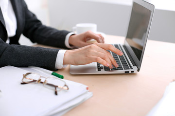 Close up of business woman  hands  typing on  laptop computer in the white colored office.