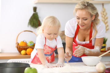 Happy family in the kitchen. Mother and child daughter cooking holiday pie or cookies for Mothers day, casual lifestyle photo series in real life interior