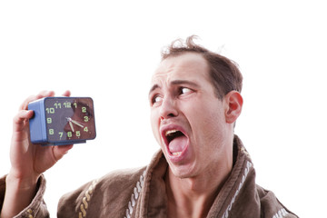 sleepy disgruntled man with alarm clock in hand early in the morning