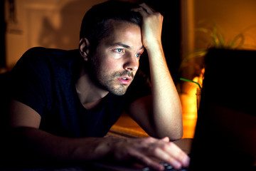 Tired man working at home. Working on computer, looking exhausted