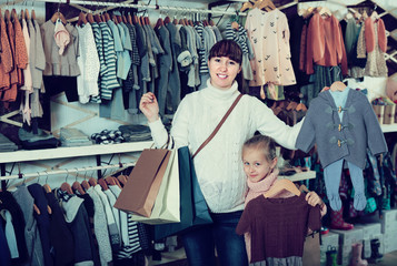 Smiling pregnant mother and daughter boasting purchases