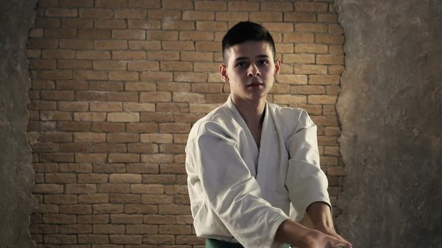 A young karateka delivering oblique chopping strike with his katana in studio