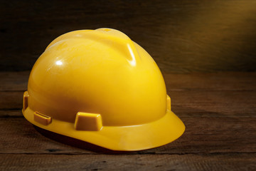 Fototapeta premium Dirty yellow safety helmet or hard hat on wood background