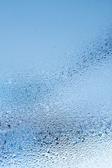 Window glass with condensation, strong, high humidity in the room, large water droplets flow down the window, cold tone, natural water drops on window glass