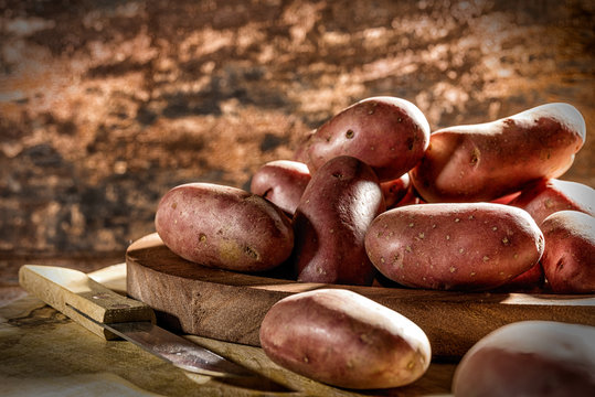 Rote Kartoffeln und Messer auf Holzbrett
