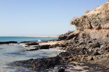 Fototapeta na wymiar Black rocks of Costa Calma beach. Blue coastline. Playa Barca, Fuerteventura, Canary islands, Spain. Istmo de la pared view