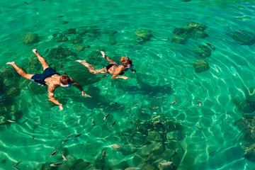 Young friends having fun snorkeling in a tropical sea with fish