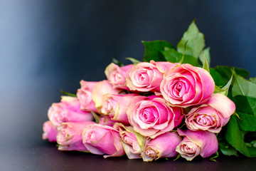 Bouquet of pink roses lies on a table on a black background