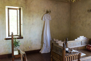 Beautiful white rustic wedding dress hanging on the chandelier in the room