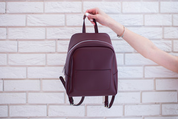 Women’s backpack of marsala color in hand on loft background 