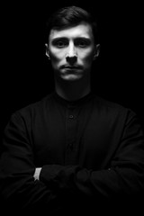 Fototapeta na wymiar Low key portrait of a man in black shirt in black and white.