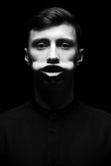 Obraz premium Niski klucz portret mężczyzny w czarnej koszuli w czerni i bieli.