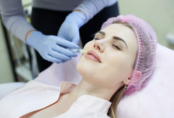 Obraz na płótnie Canvas Woman gets injection in her face. Beauty woman giving injections. Young woman gets beauty facial injections in the cosmetology salon. Face aging injection. Aesthetic Medicine, Cosmetology