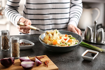 Woman eating chicken noodle soup at kitchen table