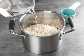 Cooking concept. Pouring water in saucepan with rice