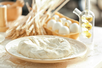 Plate with raw dough on kitchen table