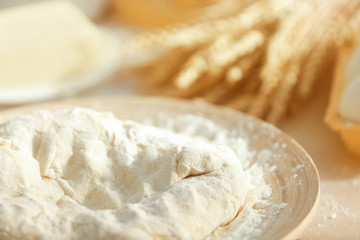 Plate with raw dough on kitchen table, closeup