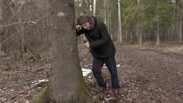 Tired hiker near tree in forest