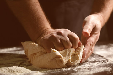 Man kneading dough in kitchen, closeup