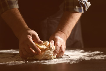 Fototapeta premium Man kneading dough in kitchen, closeup