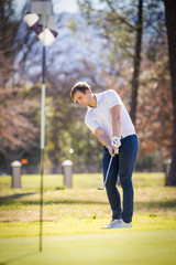 Close up view of a golfer playing a chip shot on a golf course in south africa with back light.