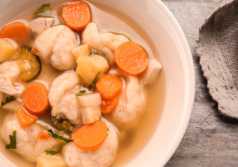 Bowl of delicious chicken and dumplings on wooden dining table