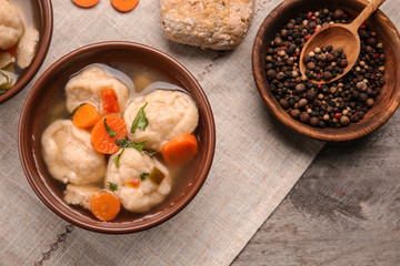 Bowl of delicious chicken and dumplings on wooden dining table
