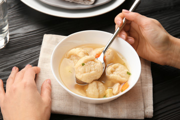 Female hands eating portion of delicious chicken and dumplings on dining table