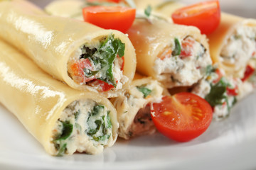 Delicious stuffed cannelloni with cherry tomatoes on plate