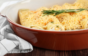 Delicious stuffed cannelloni in baking dish on table