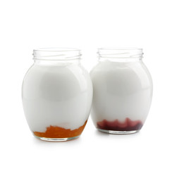 Glass jars with tasty yogurt and jam on white background