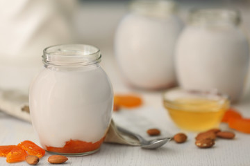 Glass jar with tasty yogurt and jam on wooden background