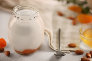 Glass jar with tasty yogurt and jam on wooden background