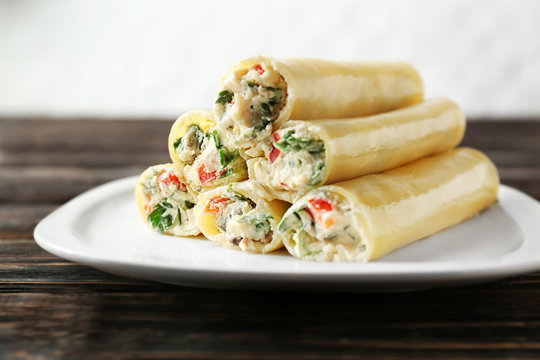Delicious stuffed cannelloni in plate on wooden table