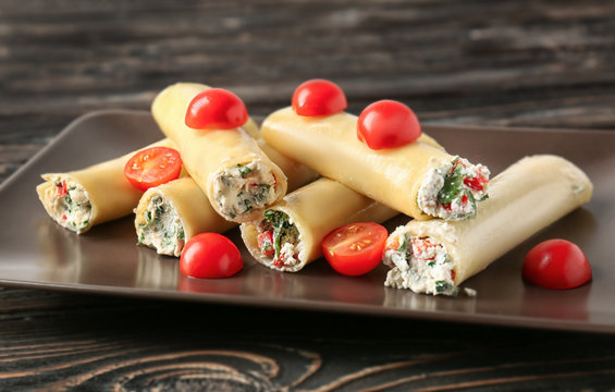 Delicious stuffed cannelloni with cherry tomatoes on wooden table