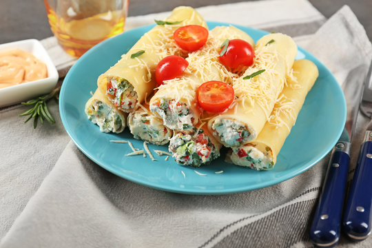 Delicious stuffed cannelloni with cherry tomatoes on blue plate
