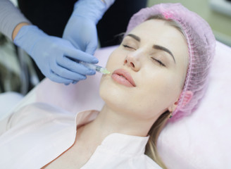 Hands of cosmetologist making injection in face, lips. Young woman gets beauty facial injections in salon. Face aging, rejuvenation and hydration procedures. Aesthetic cosmetology. Close up.