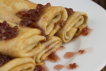 Pancakes or Russian Blintzes with jam on a plate. Wooden background. Close up
