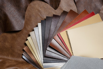 Artificial leather samples on a cow leather background. Top view.