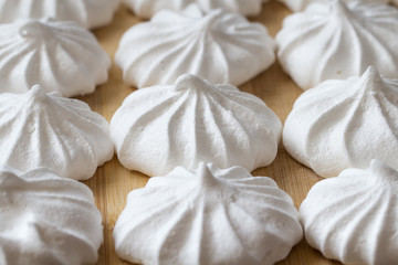 Fresh mini meringues on a wooden background.