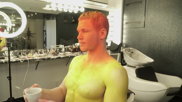 Man is art makeup is drinking coffee from a cup