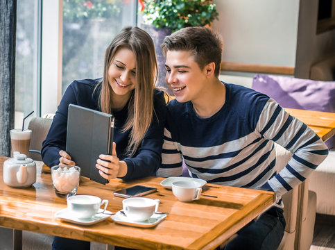 Cheerful couple dating in a cafe. They are having fun and smiling with tablet.  Dating, love, romanic, dating, lifestyle, study, education.
