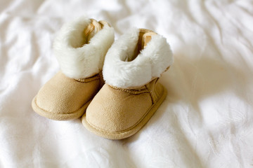 A pair of children's suede boots on the bed