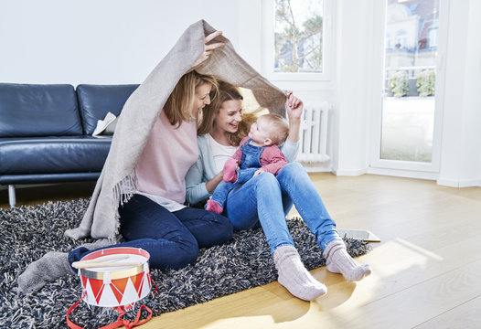 Grandmother, mother and baby girl playing in living room
