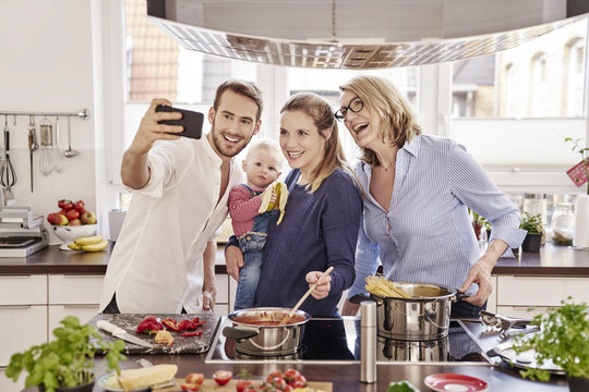 Happy family cooking in kitchen taking a selfie - Powered by Adobe