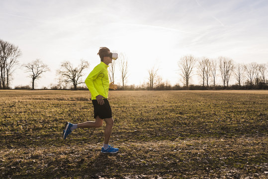 Man wearing VR glasses running in rural landscape