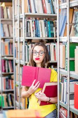 Portrait of a tired female student studying with books at the library