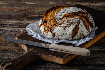 Frisch vom Bäcker: rundes Brot mit Kruste auf einem Holzbrett