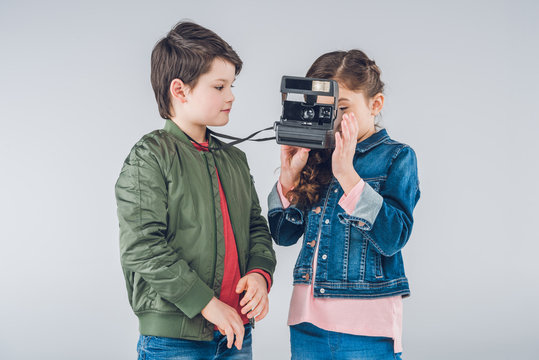 Children taking pictures on retro camera on gray