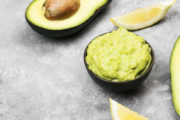 Traditional Latin American sauce guacamole in a bowl and ripe avocados and lemons. Copy space